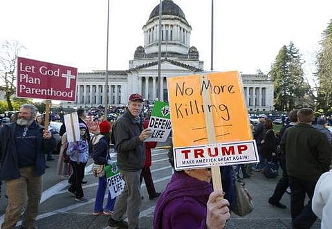 Carole Seymour, right, of Shelton, Wash., carries a sign that reads 'No More Killing' and features a sticker from the campaign of President Donald Trump as she takes part in an anti-abortion march and rally Monday, Jan. 23, 2017, at the Capitol in Olympia