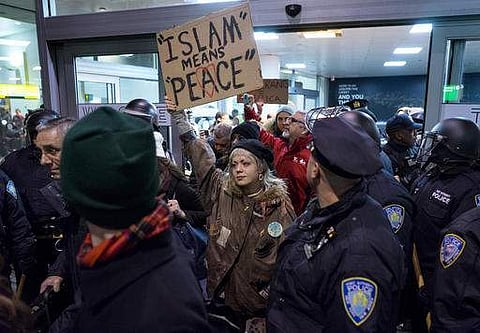Protesters are surrounded by police officers and travelers as they pass through an exit of Terminal 4 at John F. Kennedy International Airport in New York. | AP