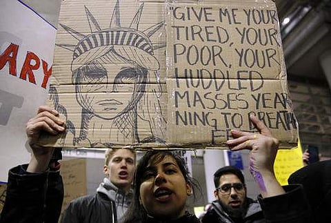 A protestor holds a placard that says 'Give me your tired, your poor, Your huddled masses yearning to breathe free'. The line is from a sonnet engraved on a plaque on the US Statue of Liberty. (Photo | AP)