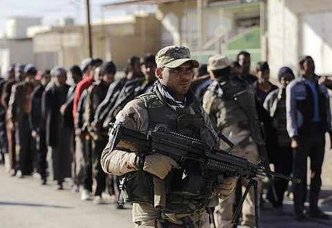 An Iraqi soldier passes scores of Iraqi male residents rounded up in hopes of offering information on any Islamic State members among them, in the Gogjali neighborhood, in Mosul.(Photo | AP)