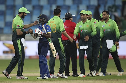 A Pakistan's player shakes hands with Sri Lanka's Akila Dananjaya as the others celebrate after they won their first ODI cricket match against Sri Lanka in Dubai, United Arab Emirates, Friday, Oct. 13, 2017. | AP