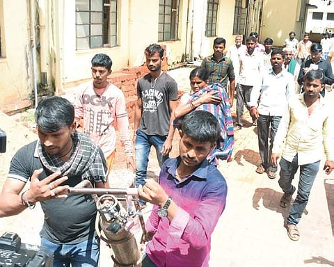 A woman carrying her sick child on her shoulder at KIMS in Hubballi. Her relatives are seen carrying the oxygen cylinder