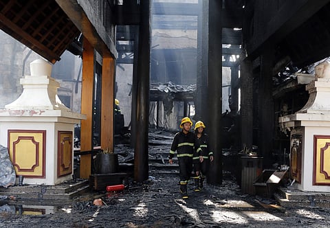 Firefighters walk at a burnt building following a fire at the Kandawgyi Palace Hotel on Thursday in Yangon, Myanmar. (AP)