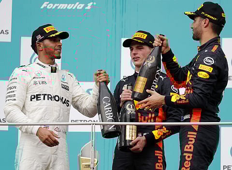 Race winner Red Bull driver Max Verstappen (C) drinks champagne with second placed Mercedes driver Lewis Hamilton (L) and third placed teammate Daniel Ricciardo (R) at the Malaysian Grand Prix. | AP