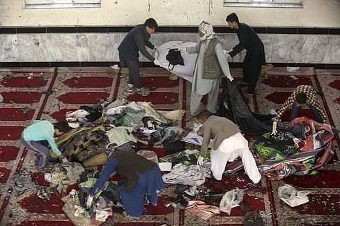 Afghan men collect remains of belongings inside a damaged mosque in Kabul, Afghanistan on Oct. 21, 2017, a day after a suicide attack. (Photo | AP)