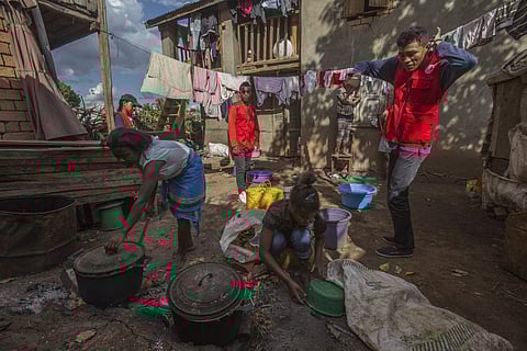 Red Cross volunteers speak to women as they are busy cooking, whilst educating villagers about the plague outbreak.
