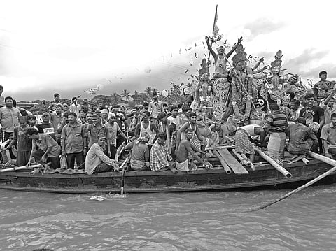 Devotees with the idol of Goddess Durga on a boat in Hansua river on Sunday | Express