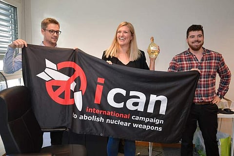 Nuclear disarmament group ICAN coordinator Daniel Hogstan, executive director Beatrice Fihn and her husband Will Fihn Ramsay pose with a banner bearing the group's logo after ICAN won the Nobel Peace Prize for its decade-long campaign to rid the world of