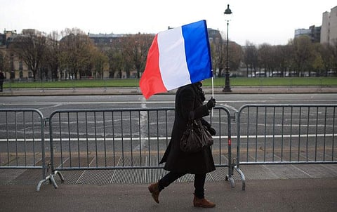 A woman carries a French flag during a ceremony in Paris on Friday honoring those killed in the Nov. 13 attacks. (Photo | AP)