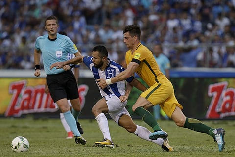Australia's Tomi Juric, right, fights for the ball with Honduras' Alfredo Mejia, center, as referee Daniele Orsato, from Italy, looks on, during the first leg of a soccer World Cup qualifier play-off at the Olympic Stadium in San Pedro Sula. | AP