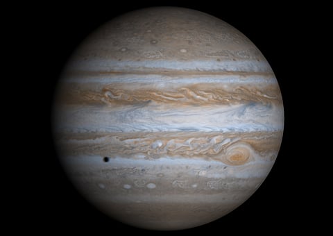 A true-color image of Jupiter taken by the Cassini spacecraft. The Galilean moon Europa casts a shadow on the planet's cloud tops. (Image Courtesy NASA)