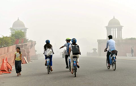 Tourists ride cycles amid mog and air pollution that reached high levels in New Delhi on Sunday. | PTI
