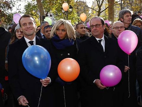 French President Emmanuel Macron, left, his wife Brigitte, and former French President Francois Hollande prepare to release balloons at Paris 11th district town hall, Monday, Nov. 13, 2017, during a ceremony held for the victims of the Paris attacks. (AP