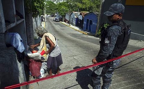 A homeless woman that was sleeping on the street leaves a police secured the area where a man and a woman were found murdred inside a bar in downtown Acapulco, Guerrero state, Mexico.|AP