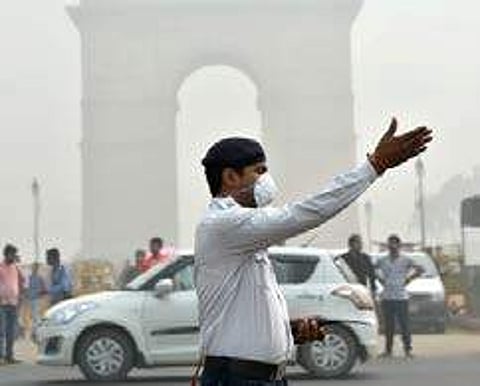 A traffic policeman wearing mask controls traffic amid smog in New Delhi. (File | PTI)