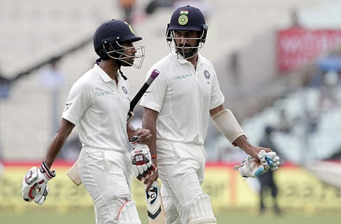 India's Wriddhiman Saha, left, and Cheteshwar Pujara leave the field after rain stopped play during the second day of the first test cricket match against Sri Lanka. | AP