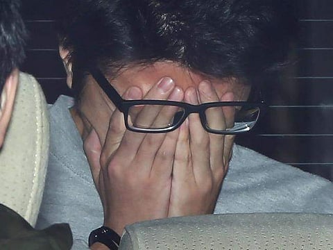 Takahiro Shiraishi covers his face with his hands as he is transported to the prosecutor's office from a police station in Tokyo on November 1, 2017. (Photo | AFP)