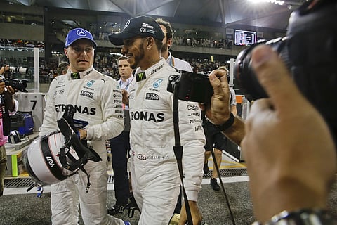 Mercedes driver Valtteri Bottas of Finland, left, pole position, looks to his teammate Mercedes driver Lewis Hamilton of Britain, second best time, after the qualifying session at the Yas Marina racetrack in Abu Dhabi. | AP