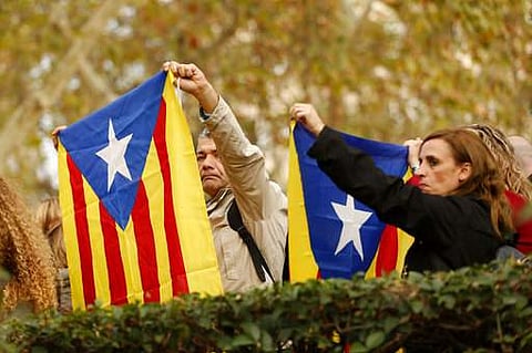 People hold up 'esteladas', or Catalonia independence flag, outside the National Court in Madrid. | AP