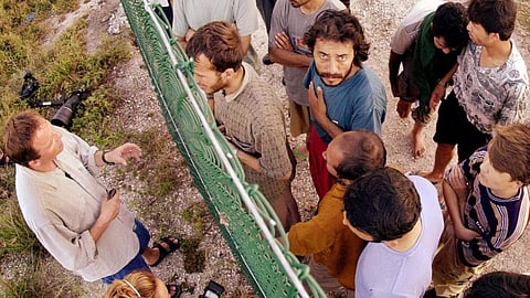 In this Sept. 19, 2001, file photo, refugees, right, gather on one side of a fence to talk with international journalists about their journey that brought them to the Island of Nauru. (Photo | Associated Press)