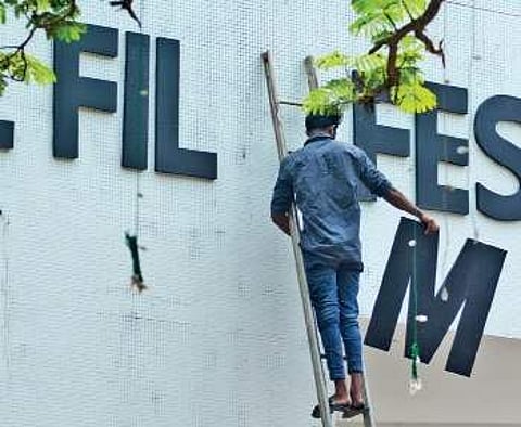 A man makes a move to fix the letter ‘M‘ on the IFFK sign board at Tagore Theatre