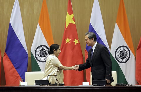 Chinese Foreign Minister Wang Yi, right, shakes hands with his Indian counterpart Sushma Swaraj. | AP