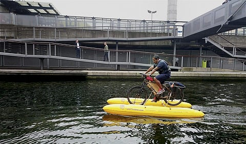 Assamese entrepreneur Dhruv Boruah rides his self-made floating bamboo bicycle down the Thames river in UK to clear discarded plastic. (Photo: PTI)