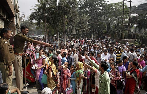 An Indian policeman asks people to wait patiently in ATM queues to exchange or deposit discontinued currency. (Photo | Associated Press)