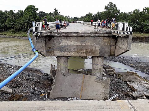 People gather on a bridge which was damaged by the onslaught of the flooding brought about by tropical storm Tembin, Sunday, Dec. 24, 2017 in Zamboanga Del Sur in southern Philippines. (Associated Press)