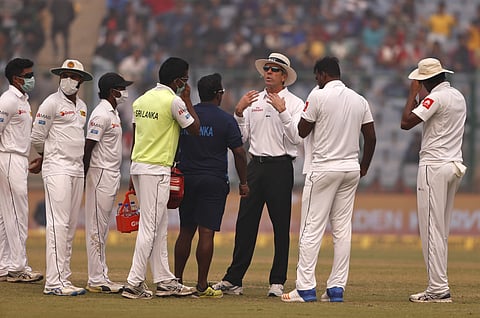 Officiating umpire Nigel Llong, third from right, speaks to Sri Lanka's players, wearing anti-pollution masks, as the game was briefly stopped during the second day of their third Test match in New Delhi, India, Sunday, Dec. 3, 2017. | AP