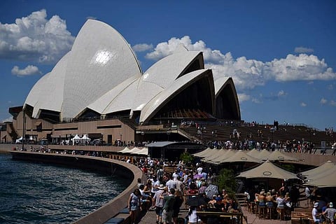 People walk along Sydney Harbour, as the Sydney Opera House is seen in the background, in Sydney. | AFP