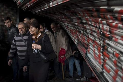 Communist-backed unionists exit from a broken entrance of the Labor ministry after they entered the building during a protest in central Athens. | AP