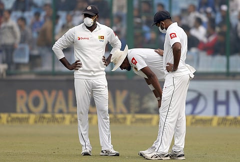 Sri Lanka's Suranga Lakmal, centre, vomits as his teammates stand next to him during the fourth day of their third Test match against India in New Delhi, India, Tuesday, Dec. 5, 2017. | AP