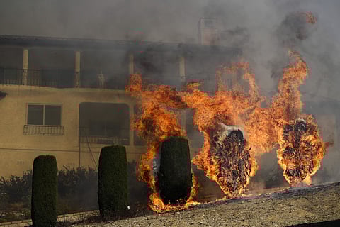 Flames rise near a home as a wildfire burns in Ventura, California. (Photo | AP)