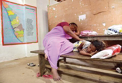 Shaila, of Nayarambalam in Vypeen islands, and her grandchild, who were shifted to the relief camp at Devi Vilasam UP School on December 1, rest on the table on Thursday. An uncertain future awaits 1,200 people at this relief camp | Albin Mathew