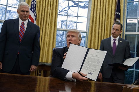 In this Jan. 23, 2017, photo, Vice President Mike Pence, left, and White House Chief of Staff Reince Priebus watch as President Donald Trump shows off an executive order to withdraw the U.S. from the 12-nation Trans-Pacific Partnership trade pact agreed t