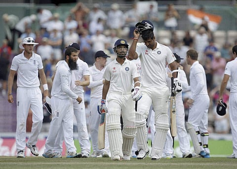 India's Ajinkya Rahane and Pankaj Singh walk off the field of play as the England team celebrate their victory after the last wicket fell of Rahane on the fifth and final day of the third cricket test match of the series between England and India in South