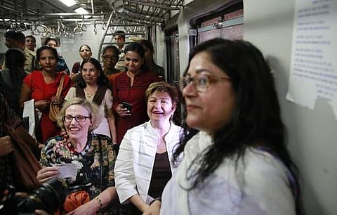 World Bank Chief Executive Officer Kristalina Georgieva, sitting right, speaks with passengers as she begins to take a trip in a suburban train in Mumbai. | AP