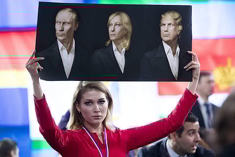 A journalist holds a poster with portraits of Russian President Vladimir Putin, left, France's far-right National Front president, Marine Le Pen, center, and President-elect Donald Trump, prior to Putin's annual news conference in Moscow. (File Photo | AP