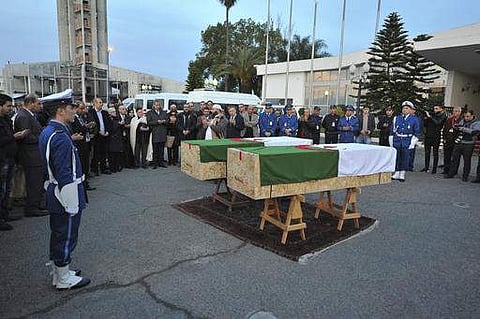 In this photo dated Saturday, Feb. 4, 2017, officials and relative of Abdelkrim Hassane and Khaled Belkacemi, stand around their flag-draped coffins during a ceremony held at Houari Boumediene airport in Algiers, Algeria. Hassane and Belkacemi were two of