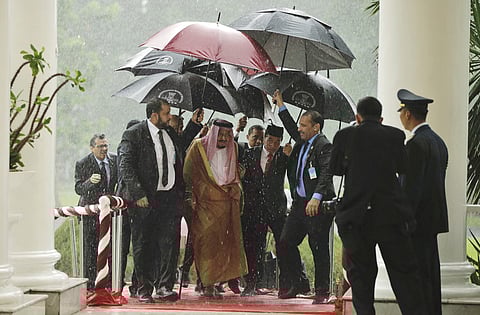 Saudi King Salman, center left, and Indonesian President Joko Widodo walk under umbrellas during heavy rain. (Photo | AP)