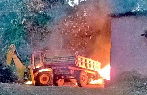 A tractor and an earth-moving equipment set on fire by a mob.