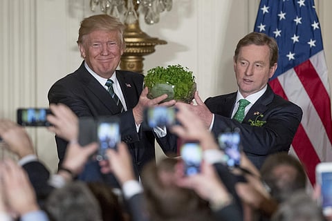 President Donald Trump, left, and Irish Prime Minister Enda Kenny, right, hold up a bowl of Irish shamrocks during a St. Patrick's Day reception in the East Room of the White House in Washington, Thursday, March 16, 2017. | AP