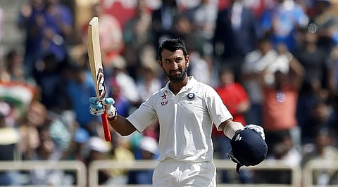 India's Cheteshwar Pujara raises his bat and helmet to celebrate scoring a century during the third day of the third test cricket match against Australia in Ranchi, India, Saturday, March 18, 2017. | AP