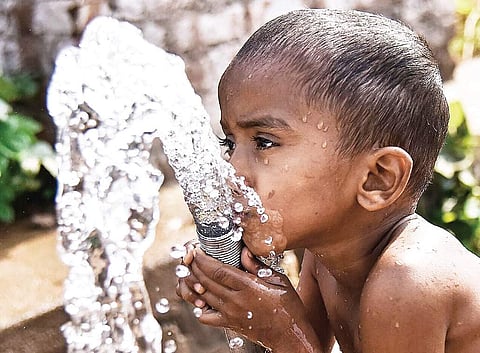 An infant drinking water from a pipeline near an agriculture land in Hyderabad on Wednesday | vinay madapu