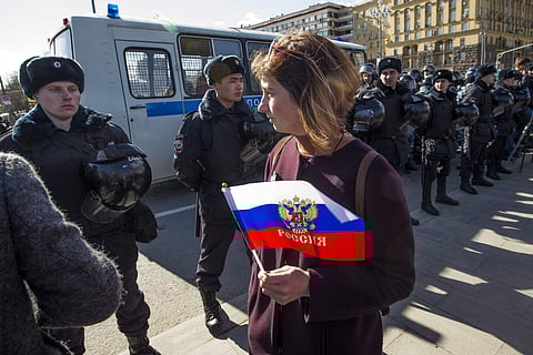 A woman with a Russian national flag walks past a Police line in Pushkin Square, downtown Moscow, Russia, Sunday, March 26, 2017. (File | AP)