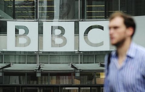 A pedestrian walks past a BBC logo at Broadcasting House in central London. | File Reuters