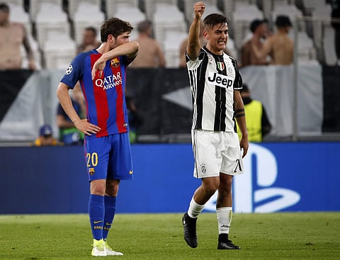Juventus's Paulo Dybala, right, celebrates past Barcelona's Sergi Roberto after scoring his side's second goal during a Champions League, quarterfinal, first-leg soccer match between Juventus and Barcelona, at the Juventus Stadium in Turin, Italy, Tuesday