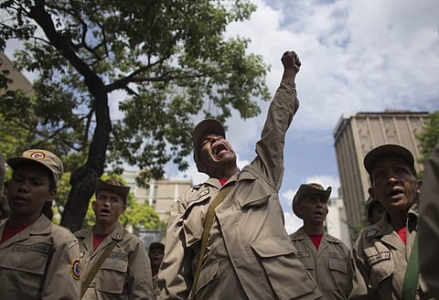 A member of the Bolivarian Militia raises his fist during the seventh anniversary celebration of the militia, in front of Miraflores presidential palace in Caracas, Venezuela. (AP)