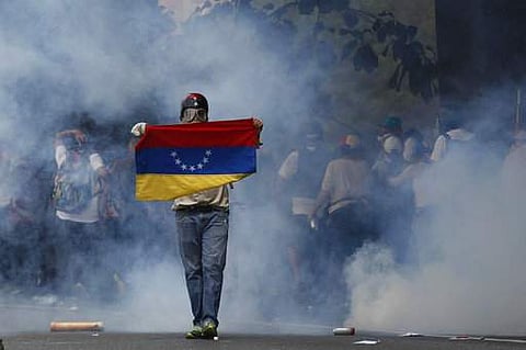 An anti-government protester holds a Venezuelan flag during clashes against security forces in Caracas on April 19. (File Photo | AP)